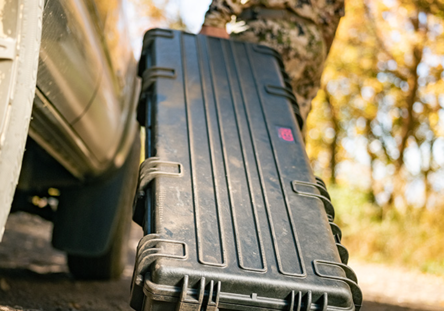 A military person carries a large Explorer 13513 gun case while trekking on a trail.