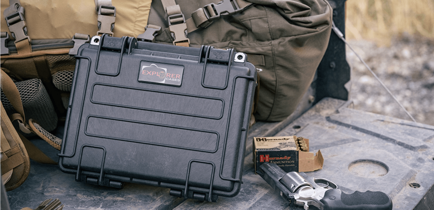 A black explorer hunting case containing a gun and various hunting accessories arranged on top.