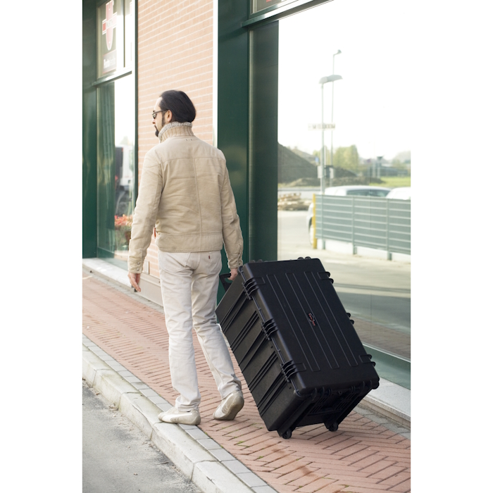 7641 TROLLEY A man walks down a sidewalk, pulling a black Explorer 7641 trolley suitcase behind him.